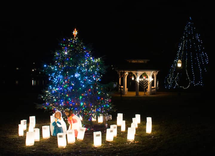 [CREDIT: Mary Carlos]  A tree in Pawtuxet Park has the Christmas treatment, with several luminaria lanterns with memorial messages written to loved ones. 