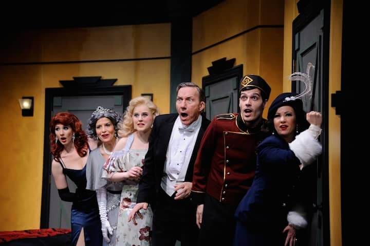 From left: Rochelle Weinrauch as Diana, Maria Tavarozzi as Julia, Elizabeth Boyke as Maggie, Alexander Cook as Saunders, Kevin Broccoli as the Bellhop, and Gerrianne Genga as Maria want to know who is in the bathroom in Ken Ludwig’s hilarious comedy, Lend Me a Tenor, being presented at Ocean State Theatre in Warwick through April 19. 