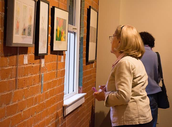 Anne Rourke, who had friends in the show, peruses the artwork on exhibit for "Colors of Spring" at Warwick Museum of Art May 13.