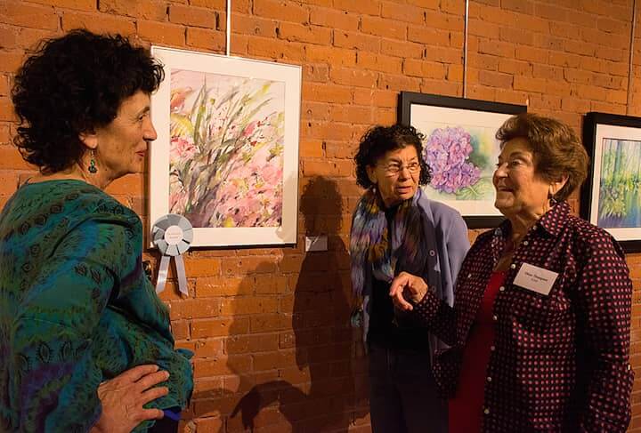 Elinor Thompson, far right, speaks with friends Nina Ackerman and Gail Lury Johnston about her Exellence-Award-winning work, "Wild Flower".