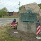 A small memorial adorned with flags alongside Warwick Avenue near Bishop Hendricken High School.