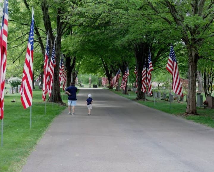 A man an boy walk along a flag-lined road inside Pawtuxet Memorial Park on Memorial Day. 