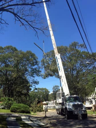 A crane removes a large tree limb from a home in the Gov. Francis Neighborhood. 