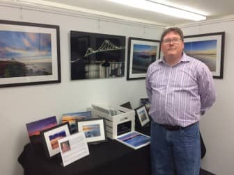 Photographer Mike Dooley with some of his photographs at the Krul Gallery in Narragansett during the opening reception for "Exploring Rhode Island".