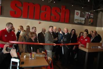 [CREDIT: Rob Borkowski] At left, center, Kevin Brown, chairman of the Mohegan Tribe, and Mayor Scott Avedisian cut the ribbon during the grand opening of Smash Burger at 1000 Bald Hill Road. After, Brown presented Avedisian and members of the Central RI Chamber of Commerce with sweet grass, a traditional Native American tradition, symbolizing good fortune.