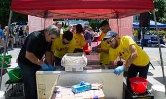 [CREDIT: Mary Carlos] The Warwick Ice Cream crew, including Vinny and Thomas Bucci, and Luis Proulx, scoop out ice cream to eager samplers at the Ice Cream Throwdown.