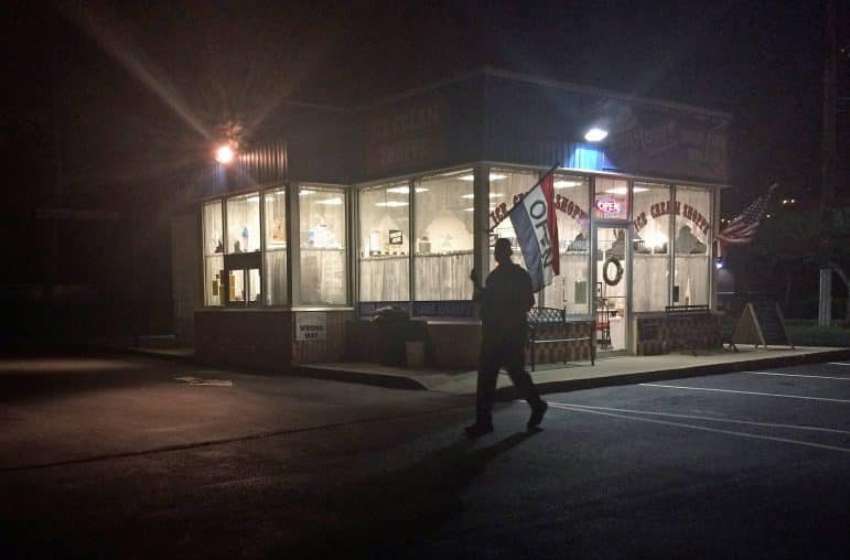 [CREDIT: Rob Borkowski] An officer patrols the lot outside Fun House Ice Cream on Post Road Aug. 11, following a reported robbery next door at Cilantro Grill.