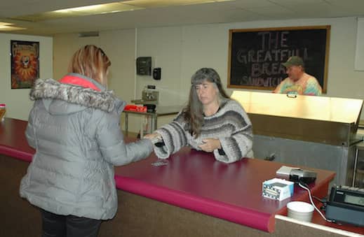 [CREDIT: Rob Borkowski] Colleen Haxton pays Christine for a sandwich as Jim Conlon makes the meal at Greatfull Bread on Post Road.