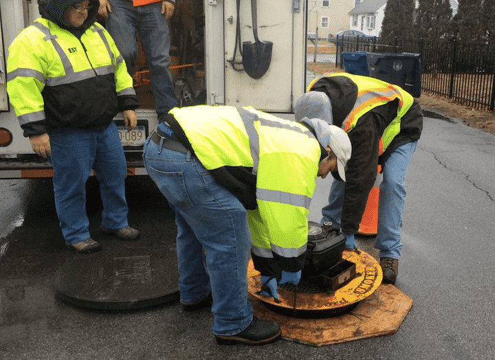 [CREDIT: Rob Borkowski] WSA subcontractors place a n air pump over a manhole on Haven Street to pump smoke through the local sewer system.