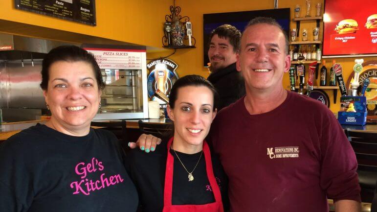[CREDIT: Rob Borkowski] From left, Lori Mirabella, Angelica Penta, and Mike Penta during opening day at Mike & Gel's Pizza April 29. Behind them is the first customer, Jared Daley.