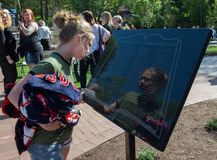 [CREDIT: Mary Carlos] Hannah Williamson looks for the name of William C. Bonardi III, her third cousin, after the dedication of the Station Fire Memorial on Cowesett Avenue in West Warwick Sunday, May 21.