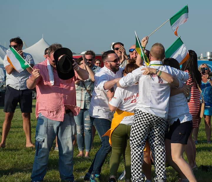 [CREDIT: Mary Carlos] A wildly excited group from Nancy’s Barn, Ballyliffin Ireland celebrate their first place win for best seafood during the Great Chowder Cook-Off at Fort Adams, Newport.