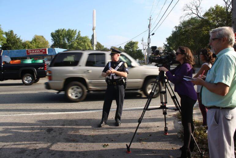 [CREDIT: Beth Hurd] Warwick Police Chief Col. Stephen McCartney watches as a pedestrian tests motorists' adherence to the law requiring them to yield for people in a crosswalk. 