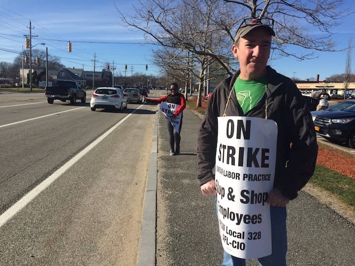 [CREDIT: Rob Borkowski] Mark Harold, grocery clerk at the Warwick Avenue Stop & Shop in Warwick, and K.D. Sabaria, front end manager at the store, wave to passing motorists honking in support of the striking workers Tuesday.