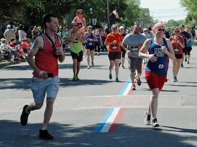 [CREDIT: Rob Borkowski] Runners near the final turn into the lot for Rhodes on the Pawtuxet during the 2019 Gaspee Days 5K Saturday.