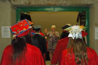 {CREDIT: Rob Borkowski] Toni Anderson, secretary at Toll Gate High, high-fives Class of 2019 graduates as they march into the CCRI field house for graduation.