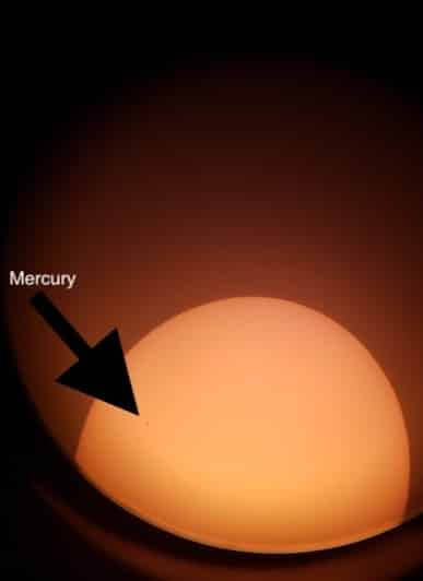 [CREDIT: Mary Carlos] People got a look through a telescope with Jason Major on the Pawtuxet River Bridge during the Transit of Mercury Nov. 11, 2019. In this photo illustration of an image taken through the telescope, Mercury is a small dot nearing the end of its travel across the view of the Sun.