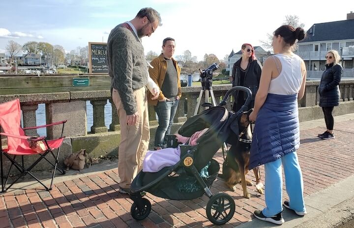 [CREDIT: Mary Carlos] From left, Toby and Michala Jorrin, with their daughter and dog, stopped to chat with Jason Major on the Pawtuxet River Bridge during the Transit of Mercury Nov. 11, 2019.