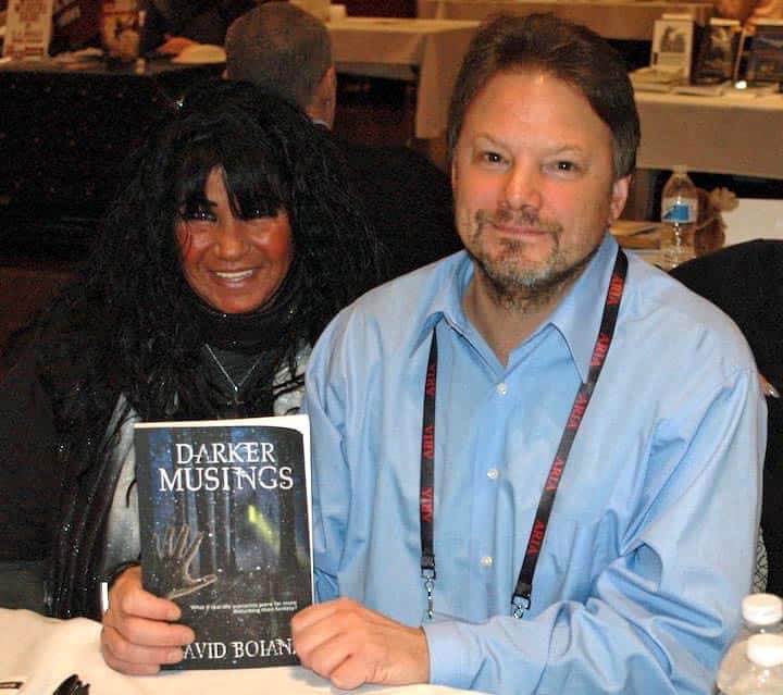 [CREDIT: Rob Borkowski] At right, author David Boiani of Coventry, shows off his short story collection, Darker Musings. At left is his friend, Coral Isabella at the RI Author Expo at Rhodes on the Pawtuxet.