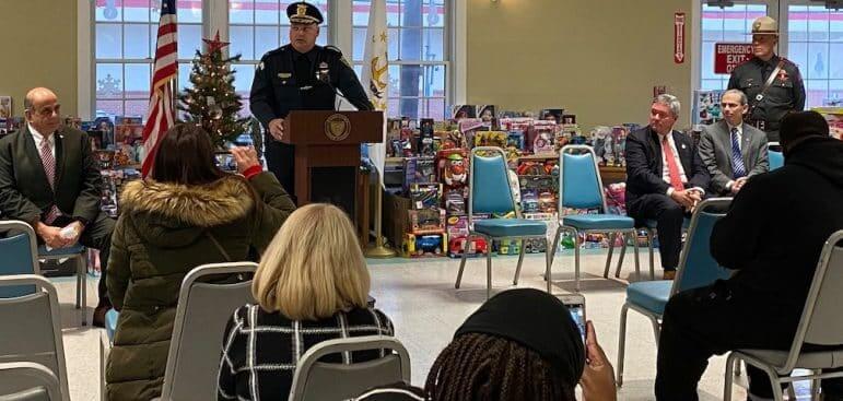 [CREDIT: RI State Police] WPD Col. Rick Rathbun speaks at Buttonwoods Community Center Dec. 17. Seated, from right, are Mayor Joseph Solomon, and U.S. Attorney Aaron L. Weisman. Standing at right is Colonel James M. Manni, Superintendent of the Rhode Island State Police.