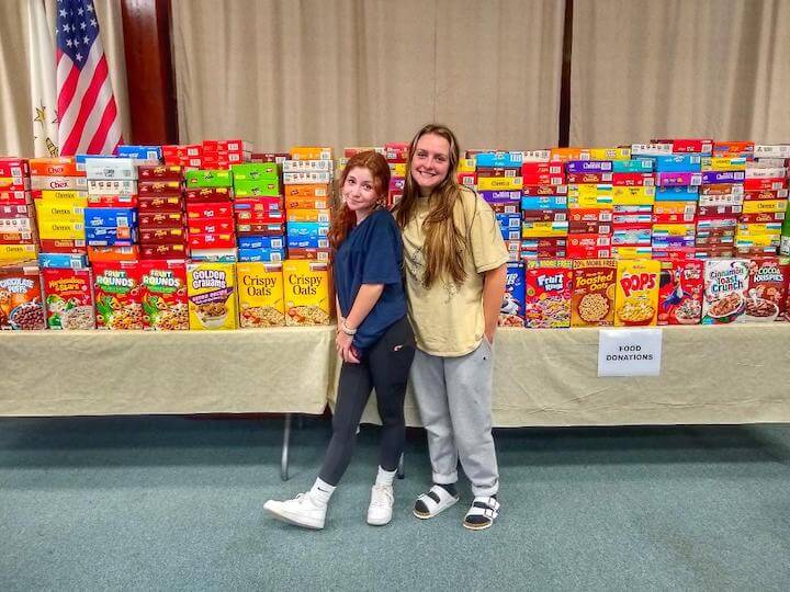[CREDIT: Linc Smith] Emily McGuire and Emma Vernet in front of the cereal collected for the Cereal Challenge.