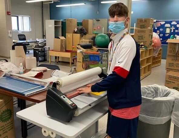 [CREDIT: Trudeau Center] Liam, a Pathways student, using one of the two laminating machines a Fogerty Foundation grant afforded the Trudeau Center.