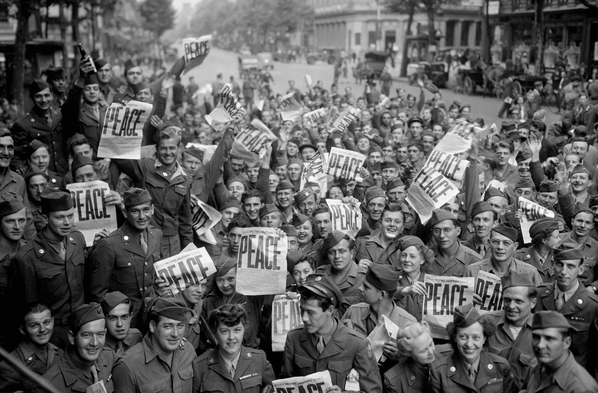 [CREDIT: National Archives] American service members gather in front of the Red Cross club in Paris to celebrate the unconditional surrender of the Japanese, Aug. 15, 1945.