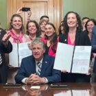 [CREDIT: Legislative Press & Public Information Bureau] Gov. Dan McKee, seated, signed the Equality in Abortion Coverage Act, with sponsors Katherine S. Kazarian, to the left of him holding bill, and Sen. Bridget Valverde, to his right holding bill. At left is House Speaker K. Joseph Shekarchi and at right is Senate Majority Leader Ryan W. Pearson.