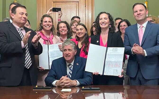 [CREDIT: Legislative Press & Public Information Bureau] Gov. Dan McKee, seated, signed the Equality in Abortion Coverage Act, with sponsors Katherine S. Kazarian, to the left of him holding bill, and Sen. Bridget Valverde, to his right holding bill. At left is House Speaker K. Joseph Shekarchi and at right is Senate Majority Leader Ryan W. Pearson.