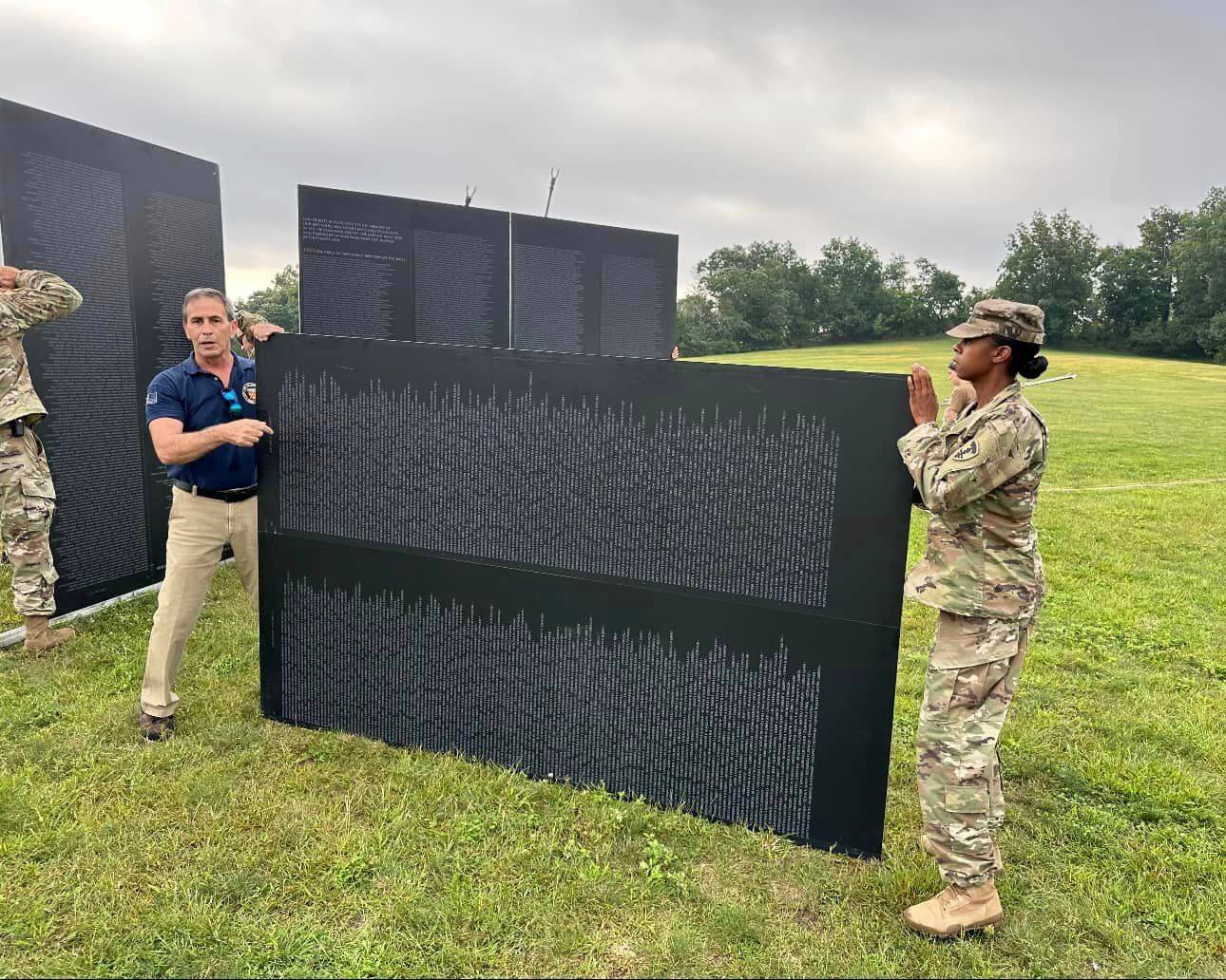 [CREDIT: Mayor Picozzi's Office] Mayor Frank Picozzi helps assemble the Traveling Vietnam Memorial Wall at Rocky Point Park Friday. The replica of the Washington DC monument is open to the public through Sunday, 5 p.m.