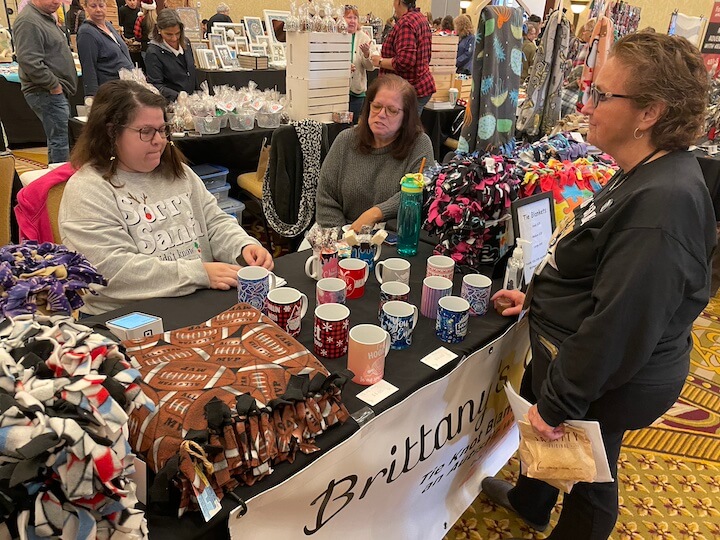 [CREDIT: Rob Borkowski] Brittany and her mom enjoy a brisk sales day for their shop, Brittany's Crafty Corner, during Shop RI's Small Business Saturday expo at Crowne Plaza Nov. 25, 2023.