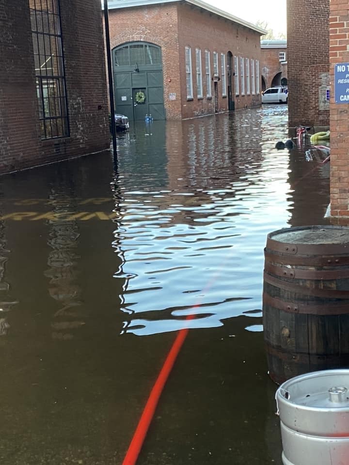 [CREDIT: Mayor Frank Picozzi] Flooding from the Dec. 18 2023 storm at the front lot of Apponaug Brewing Company in Pontiac Village, next to Pontiac Mills Apartments on Knight Street. Pictured here, the lot access between the brewery and the apartments. To the left, around the corner, is the brewery's outdoor dining area
