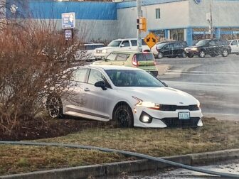 [CREDIT: Lincoln Smith] A car was stuck in muddy grass at the entrance to Shaw's parking lot on Warwick Ave. Wednesday, Dec. 20, 2023.