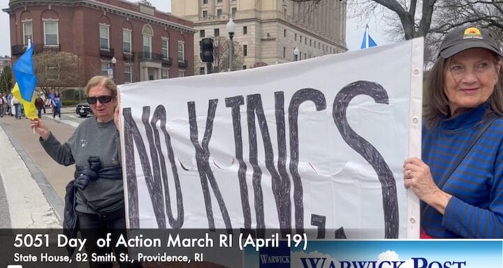 Two Newport, RI women hold a sign reading "No Kings" on the sidewalk outside the State House April 19 during a repeat "Hands Off" protest against the Trump Administration.