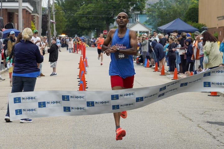 [CREDIT: Laura Paton] Gilmar Silvestre of Tauton MA crosses the finish line first with a time of 14:20 during the June 14 Gaspee Days 5k.