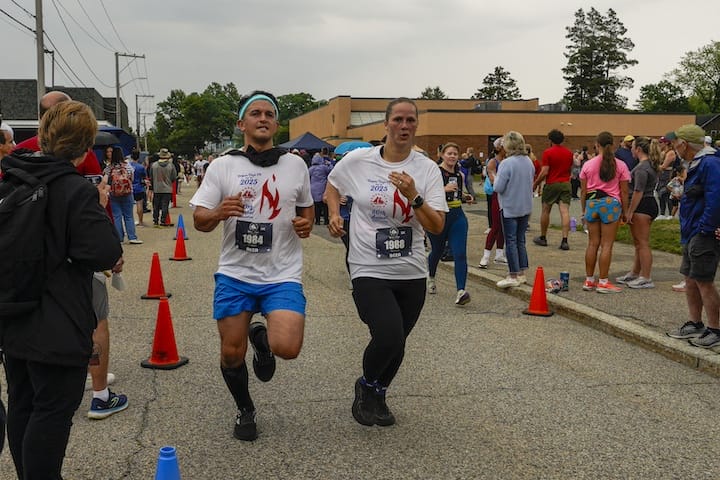 [CREDIT: Laura Paton] Brandon and Jenarita Plante of Coventry cross the finish line together at the Gaspee Days 5K June 14, 2025.