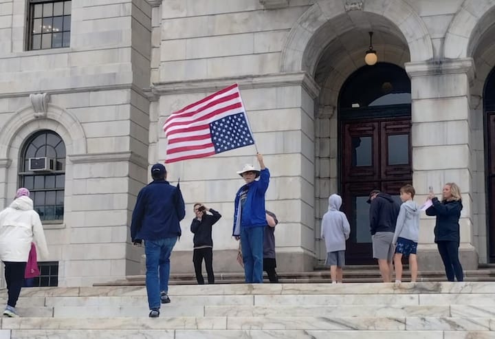 [CREDIT: Jim Taylor] Thousands attended the third 'No Kings' rall June 14 at the State House. Above, a man holds an upside-down American flag, a recognized signal of distress.