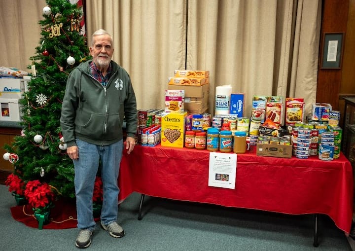 [CREDIT: Bob Mattera,President, PSRI] Lakewood Baptist and Photographic Society of RI (PSRI) member Lincoln Smith with the food soon to be delivered to West Bay Marketplace following the PSRI Christmas Food Collection for 2025.