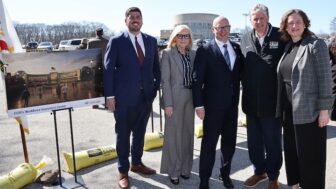 [CREDIT: CCRI] From left, Rep. Joe Solomon (Warwick), CCRI President Rosemary Costigan, Patrick Crowley (AFL-CIO), Governor Dan McKee, and Mary Barden (NEA-RI), beside an Artist's rendering of the proposed $60M CCRI Workforce Innovation Center